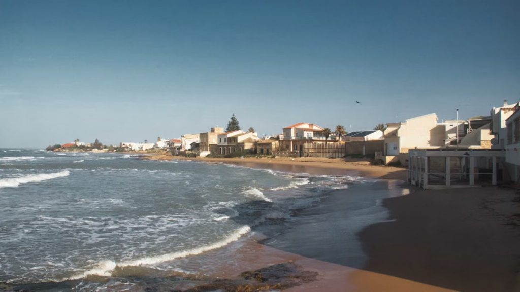 Beautiful coastal view of a sandy beach in Sicily, Italy under a clear blue sky.
